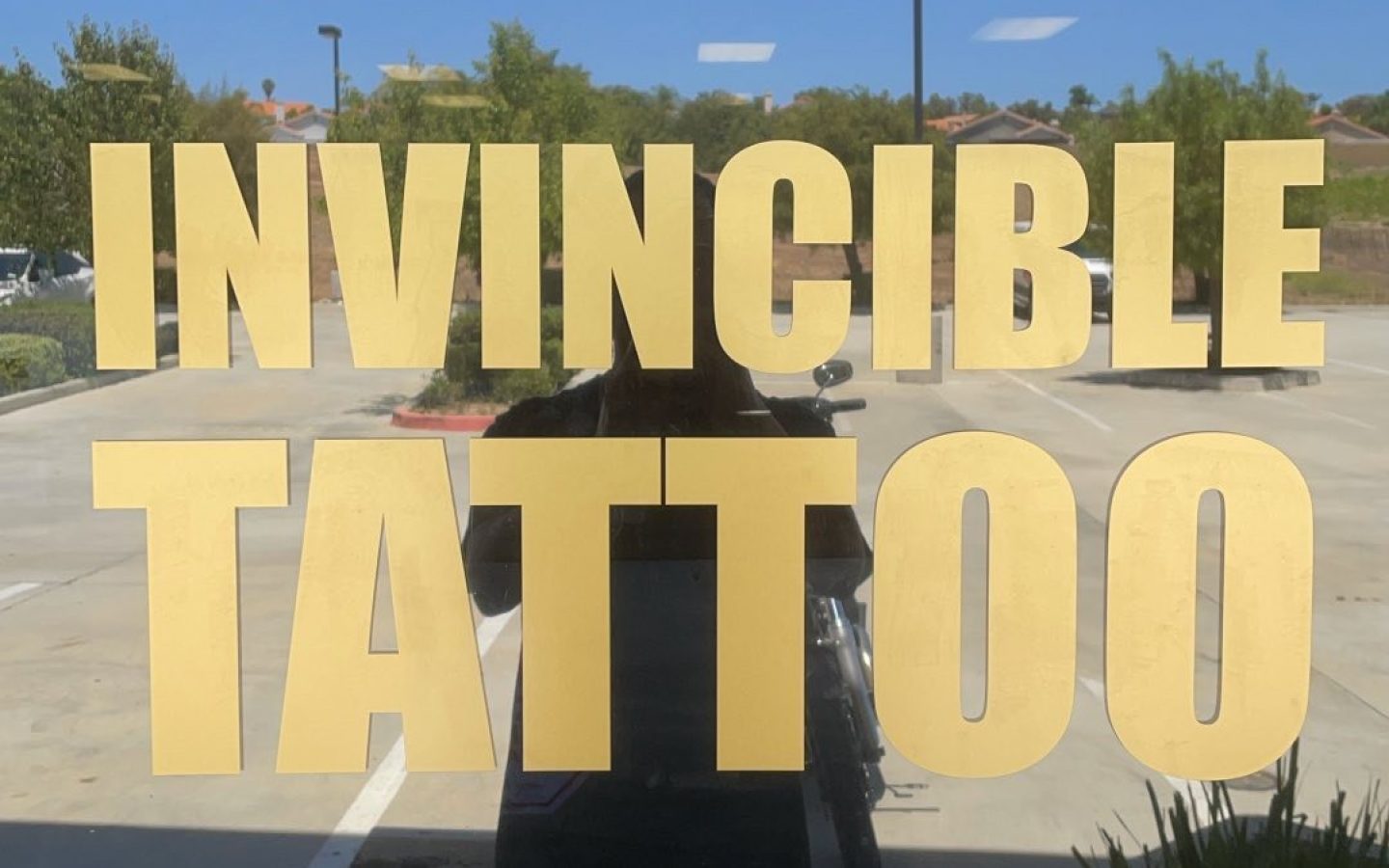 The gold Invincible Tattoo lettering on the studio window